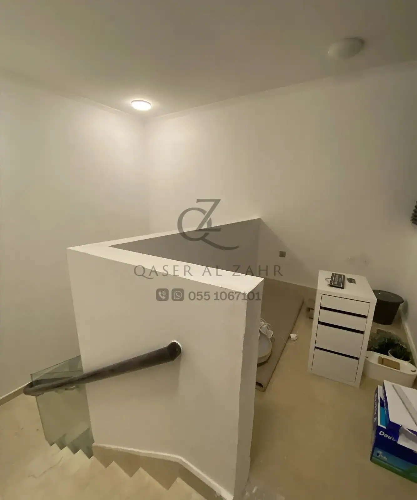 Indoor staircase with glass railing and aluminum-framed partition, office setup in progress.