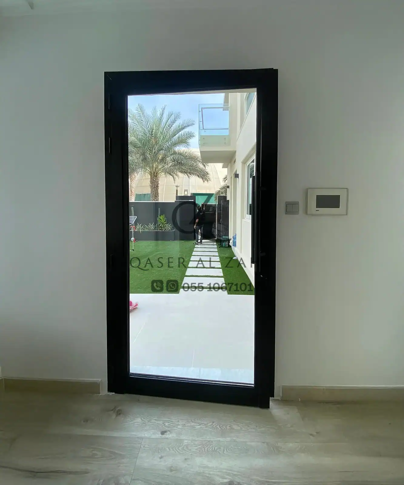 Glass door with black frame opening to modern outdoor area